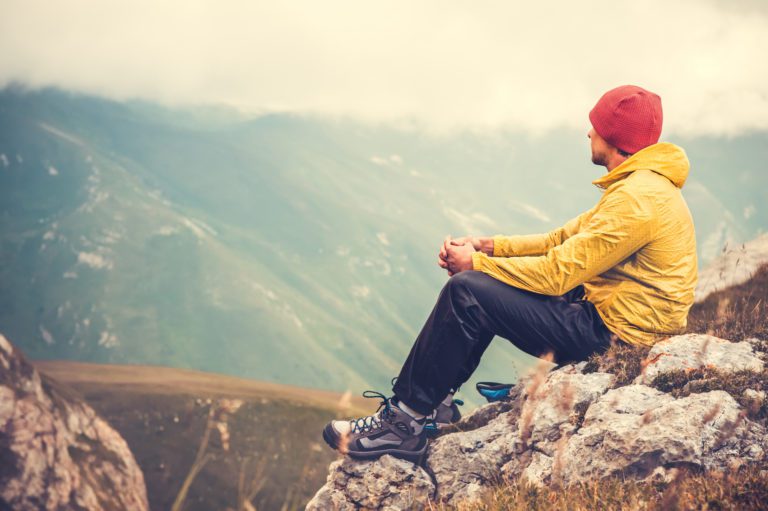 Man sitting on the top of a mountain alone.